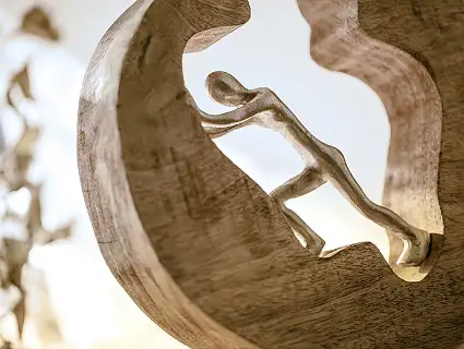 schiebende Bronzefigur in einem Rad aus Holz